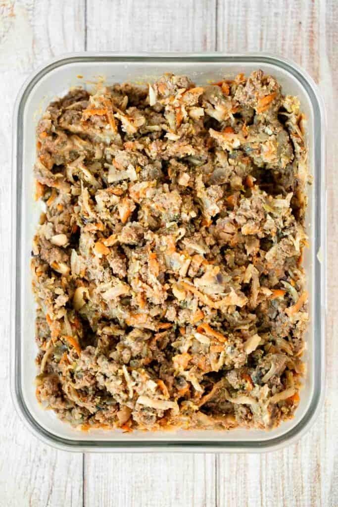 Cooked ground beef filling with carrots and onion in a glass storage container