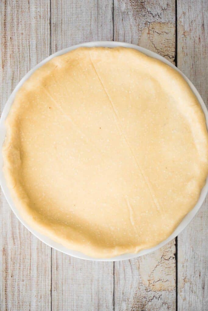 Second pie crust rolled out and draped over a pie dish and trimmed
