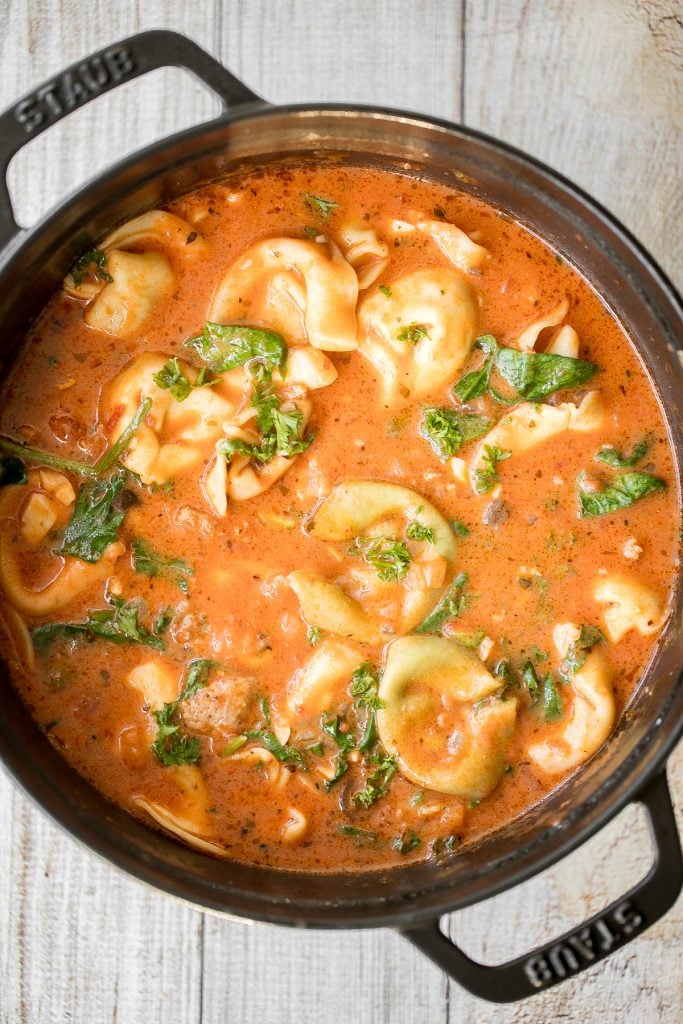 Hearty and creamy tortellini soup with sausage, spinach and kale is total comfort food in a bowl. Make this flavourful one pot meal in under 30 minutes. | aheadofthyme.com