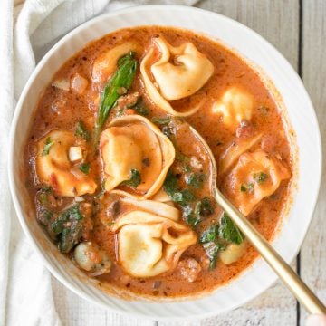 Hearty and creamy tortellini soup with sausage, spinach and kale is total comfort food in a bowl. Make this flavourful one pot meal in under 30 minutes. | aheadofthyme.com