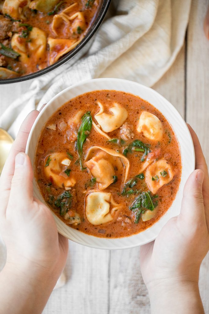Hearty and creamy tortellini soup with sausage, spinach and kale is total comfort food in a bowl. Make this flavourful one pot meal in under 30 minutes. | aheadofthyme.com