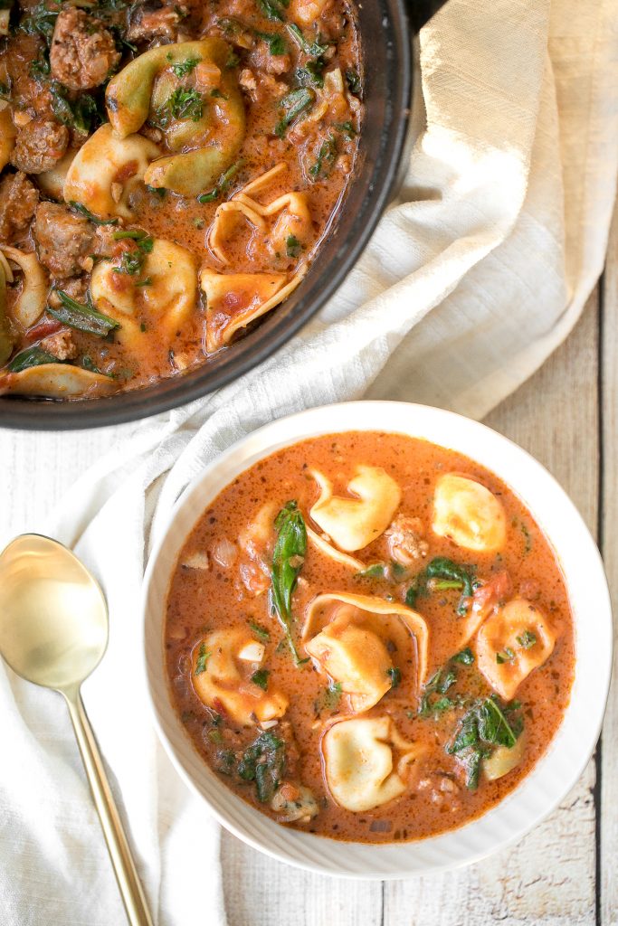 Hearty and creamy tortellini soup with sausage, spinach and kale is total comfort food in a bowl. Make this flavourful one pot meal in under 30 minutes. | aheadofthyme.com