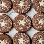 Soft and warmly spiced gingerbread linzer cookies with white chocolate ganache and dusted with confectioners' sugar is a delicious Christmas holiday cookie. | aheadofthyme.com