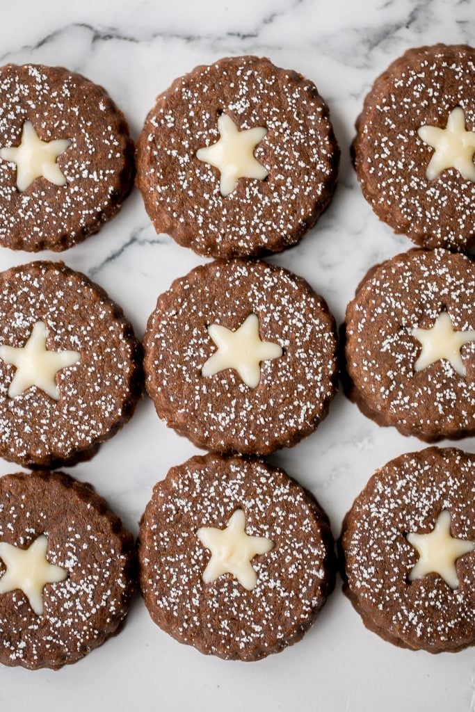 Soft and warmly spiced gingerbread linzer cookies with white chocolate ganache and dusted with confectioners' sugar is a delicious Christmas holiday cookie. | aheadofthyme.com