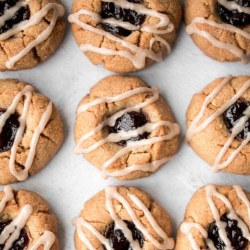 Melt-in-your-mouth peanut butter thumbprint cookies with raspberry jam and a drizzle of maple cinnamon glaze are the best holiday cookies and easy to make. | aheadofthyme.com