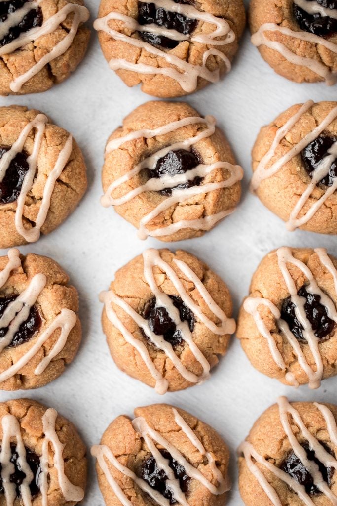 Melt-in-your-mouth peanut butter thumbprint cookies with raspberry jam and a drizzle of maple cinnamon glaze are the best holiday cookies and easy to make. | aheadofthyme.com