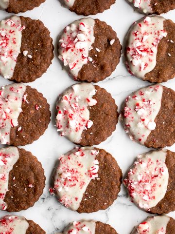 Festive white chocolate peppermint gingerbread cookies are soft and chewy, dipped in white chocolate, with a sprinkle of crushed peppermint candy canes. | aheadofthyme.com