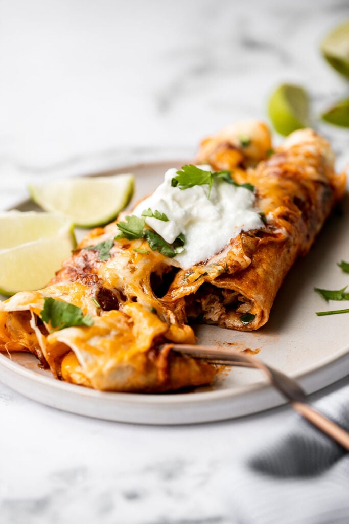 Easy baked chicken enchiladas brings the taste of authentic Mexican food into your kitchen -- saucy, spicy, and savoury. Perfect for a Mexican fiesta. | aheadofthyme.com