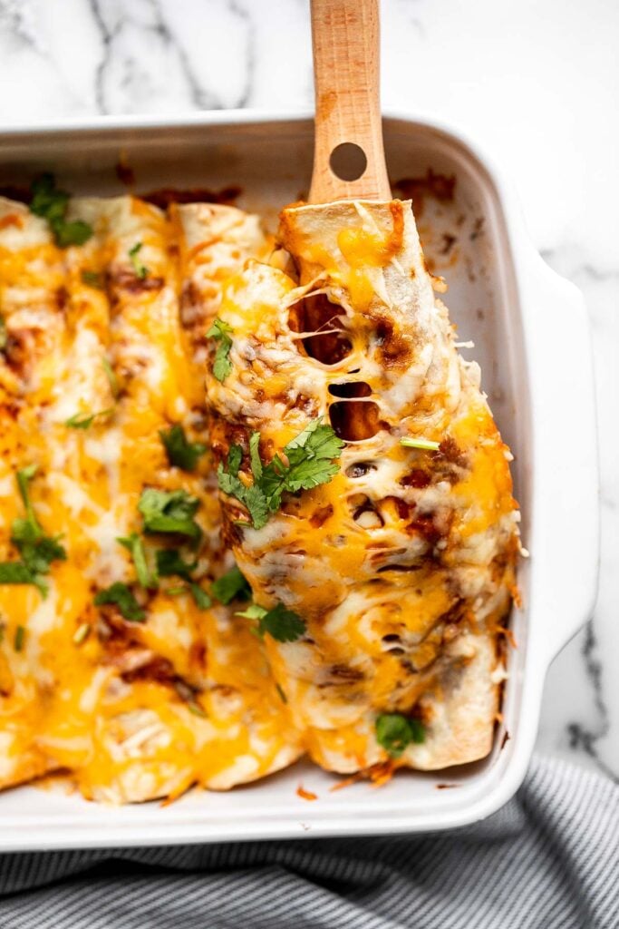 Easy baked chicken enchiladas brings the taste of authentic Mexican food into your kitchen -- saucy, spicy, and savoury. Perfect for a Mexican fiesta. | aheadofthyme.com