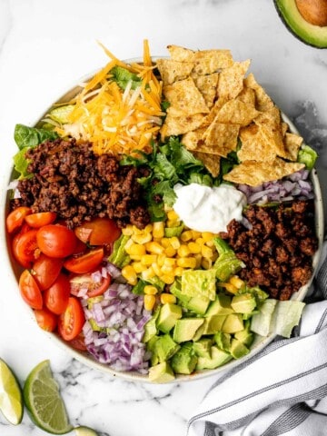 Beef taco salad is a simple, filling, and delicious meal loaded with your favorite taco fillings, and a creamy lime dressing. Make it in 20 minutes. | aheadofthyme.com