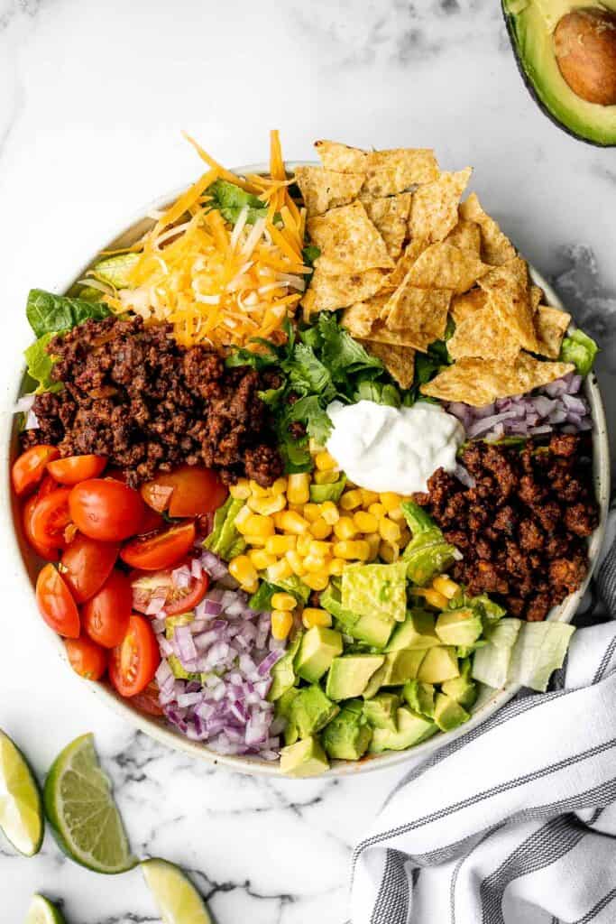 Beef taco salad is a simple, filling, and delicious meal loaded with your favorite taco fillings, and a creamy lime dressing. Make it in 20 minutes. | aheadofthyme.com