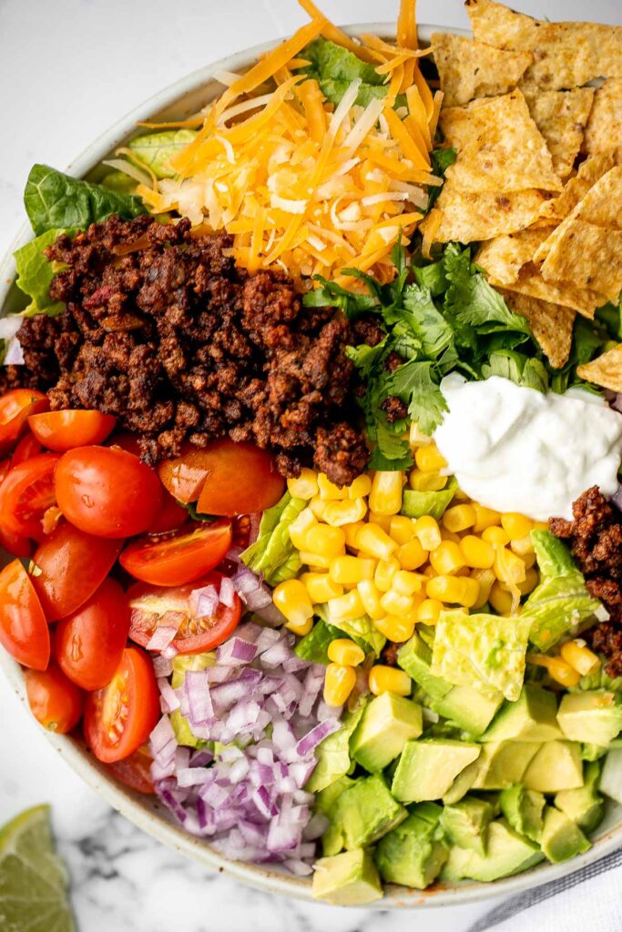 Beef taco salad is a simple, filling, and delicious meal loaded with your favorite taco fillings, and a creamy lime dressing. Make it in 20 minutes. | aheadofthyme.com
