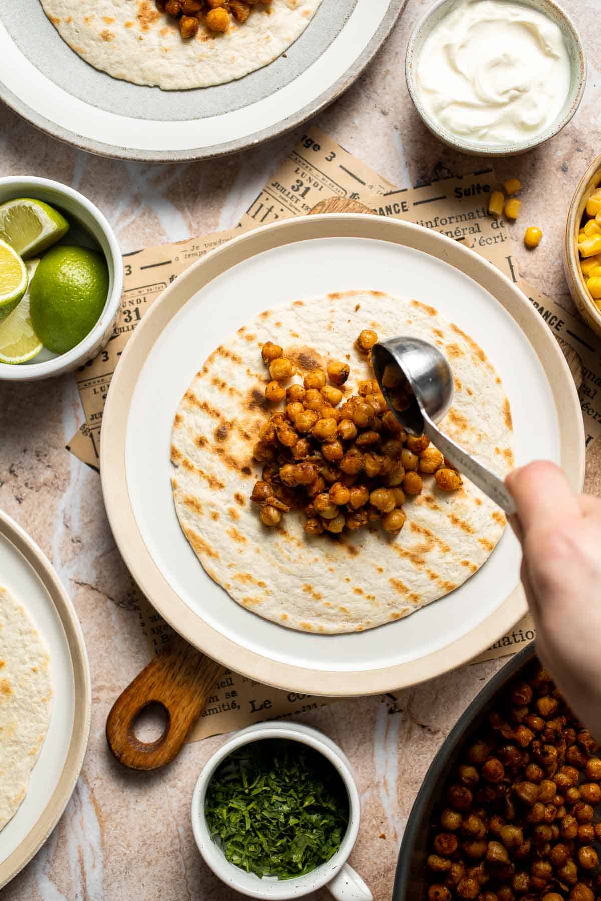 Spiced chickpea taco filling being added to a tortilla.