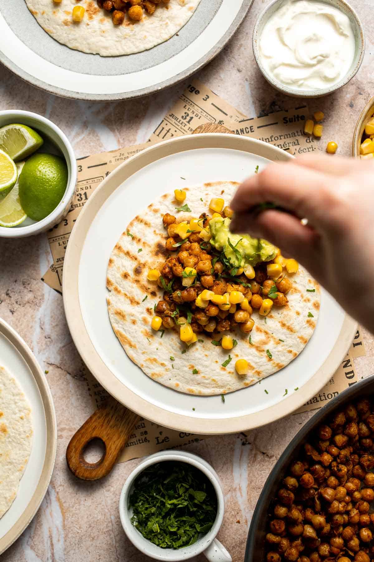 Fresh cilantro being added to a chickpea taco.