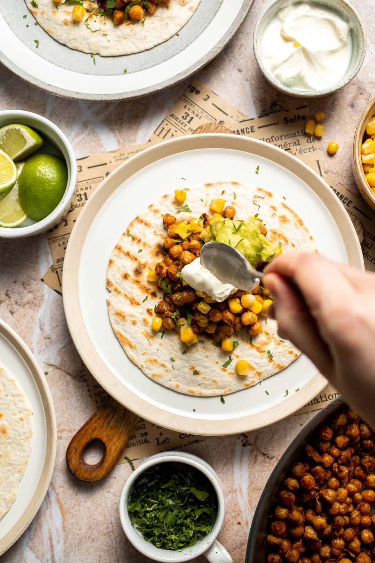 Sour cream being added to a vegan chickpea taco.