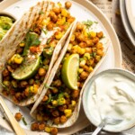 Healthy vegan chickpea tacos with seasoned chickpeas, guacamole, corn, cilantro, and lime. Easy plant-based taco recipe.