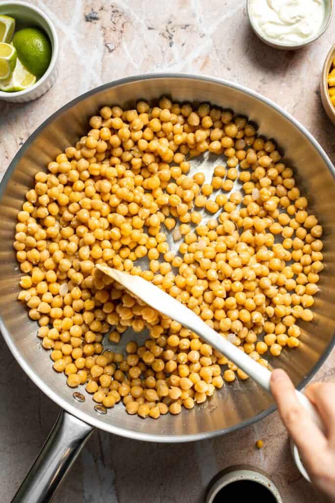 Chickpeas sautéing in a skillet until lightly golden.