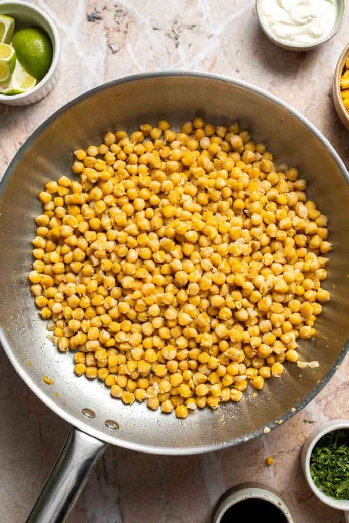 Cooked chickpeas browning in a skillet.