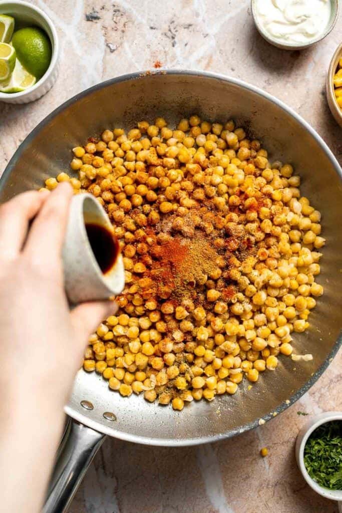 Soy sauce being added to seasoned chickpeas.
