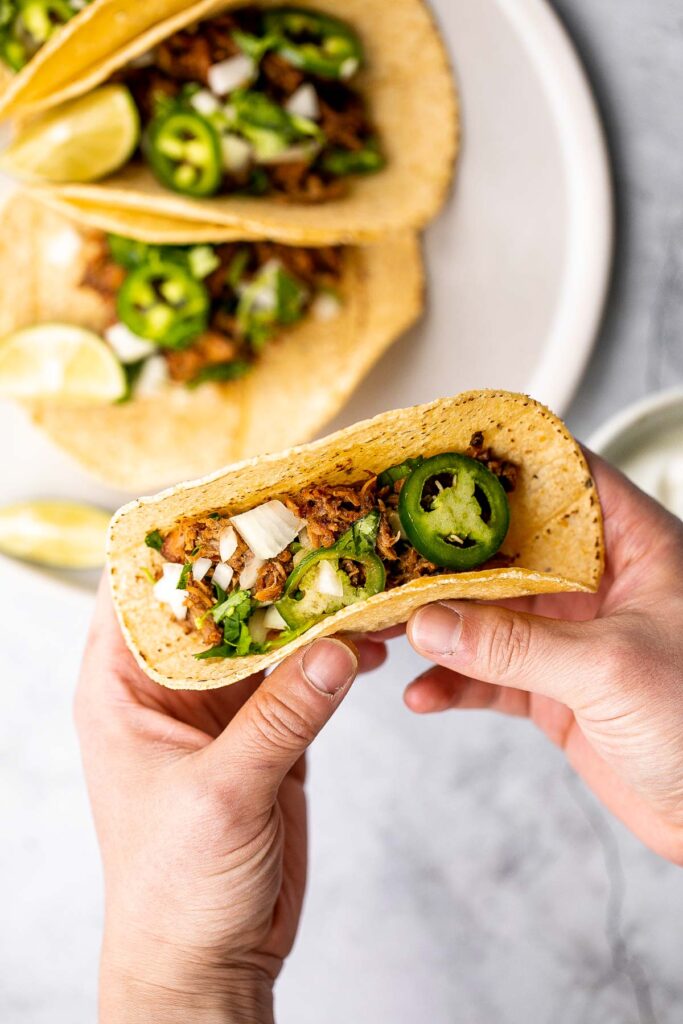 Mexican pulled pork tacos with juicy and tender traditional carnitas wrapped in corn tortillas and topped with fresh onions, cilantro, and jalapeños. | aheadofthyme.com