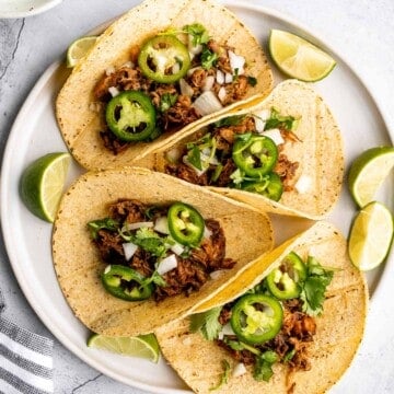 Mexican pulled pork tacos with juicy and tender traditional carnitas wrapped in corn tortillas and topped with fresh onions, cilantro, and jalapeños. | aheadofthyme.com