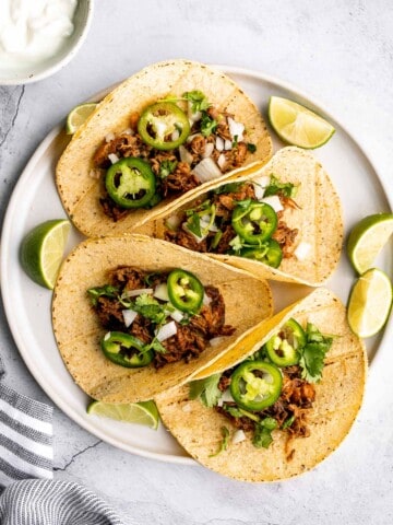 Mexican pulled pork tacos with juicy and tender traditional carnitas wrapped in corn tortillas and topped with fresh onions, cilantro, and jalapeños. | aheadofthyme.com