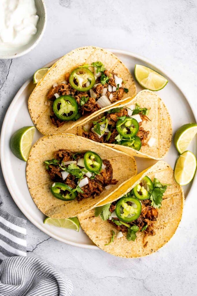 Mexican pulled pork tacos with juicy and tender traditional carnitas wrapped in corn tortillas and topped with fresh onions, cilantro, and jalapeños. | aheadofthyme.com