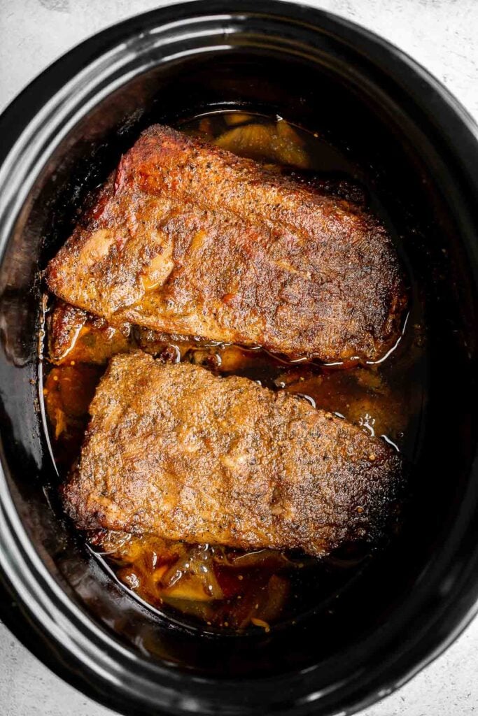 Slow cooker BBQ ribs are juicy, saucy, and tender -- the meat literally falls right off the bone. Add this easy recipe to your list of crockpot recipes. | aheadofthyme.com