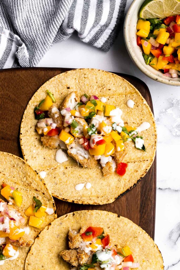 Fish stick tacos are fun, quick, easy, and delicious. Crispy breaded fish sticks are topped with a homemade mango salsa and a drizzle of lime crema. | aheadofthyme.com