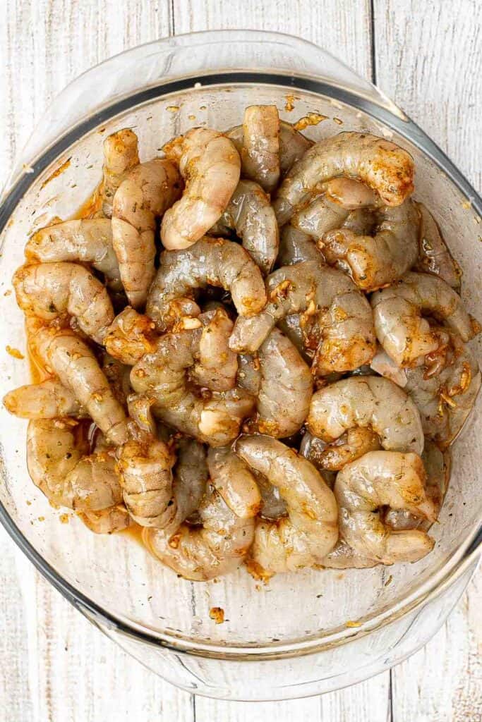 Raw shrimp tossed in a garlic lemon marinade for garlic shrimp skewers.