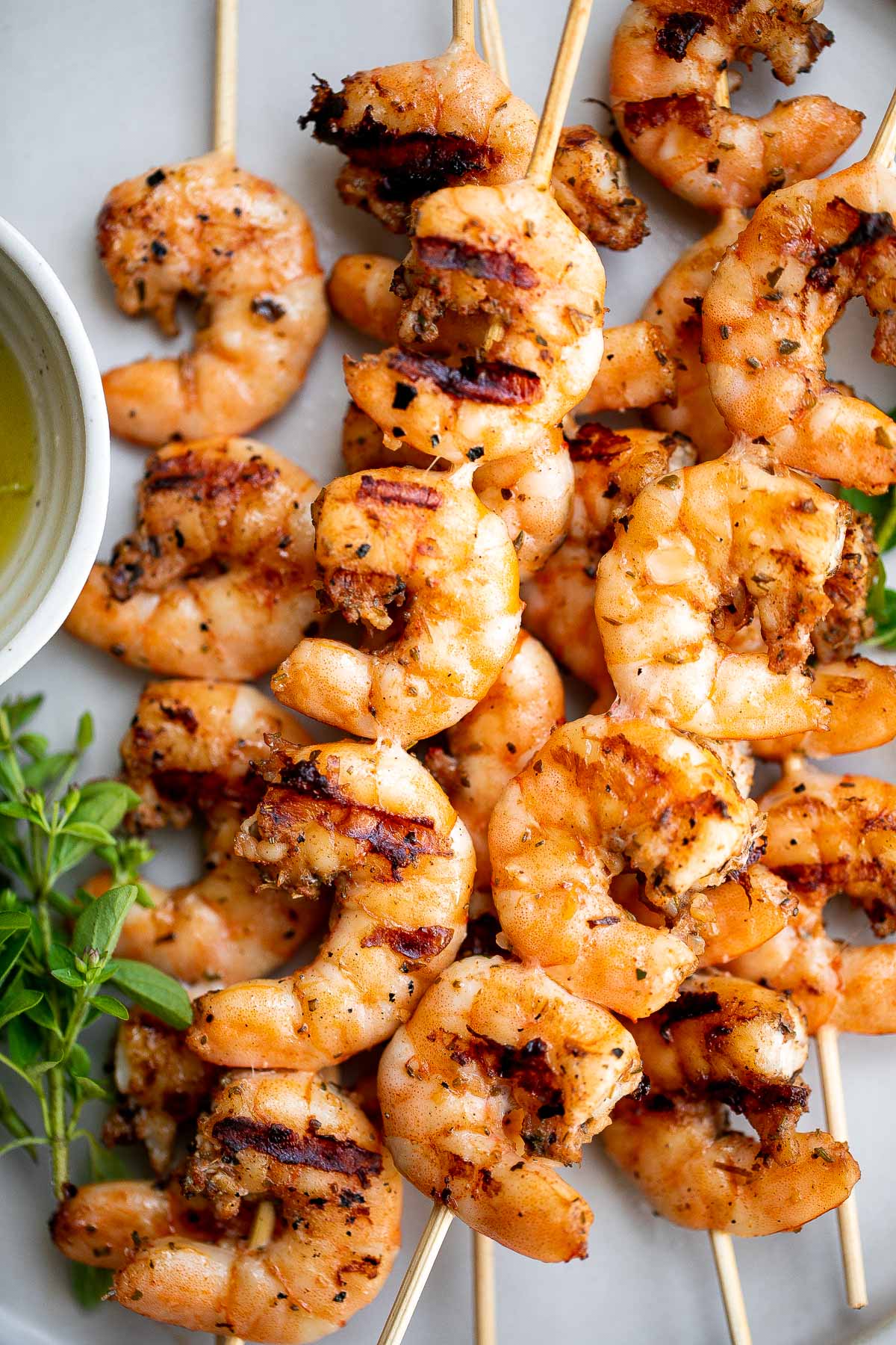 Close up of grilled garlic shrimp skewers with charred edges and fresh herbs.