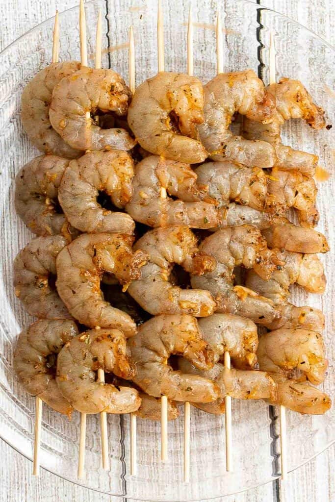 Marinated shrimp threaded onto wooden skewers and ready to grill.