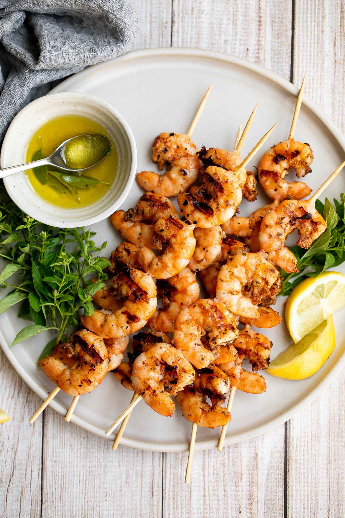 Grilled garlic shrimp skewers served with fresh parsley and lemon slices.