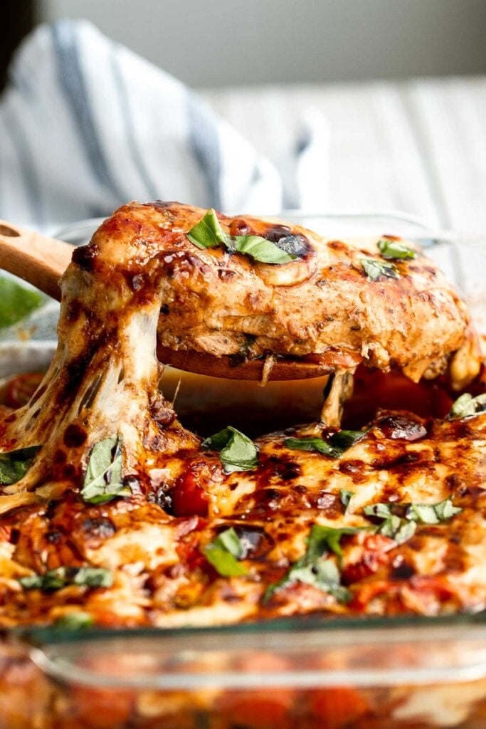 Baked caprese chicken is tender, juicy, and delicious, topped with burst tomatoes, mozzarella cheese, fresh basil, and a drizzle of balsamic glaze. | aheadofthyme.com