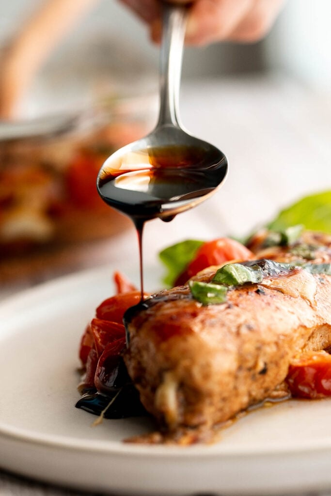 Baked caprese chicken is tender, juicy, and delicious, topped with burst tomatoes, mozzarella cheese, fresh basil, and a drizzle of balsamic glaze. | aheadofthyme.com