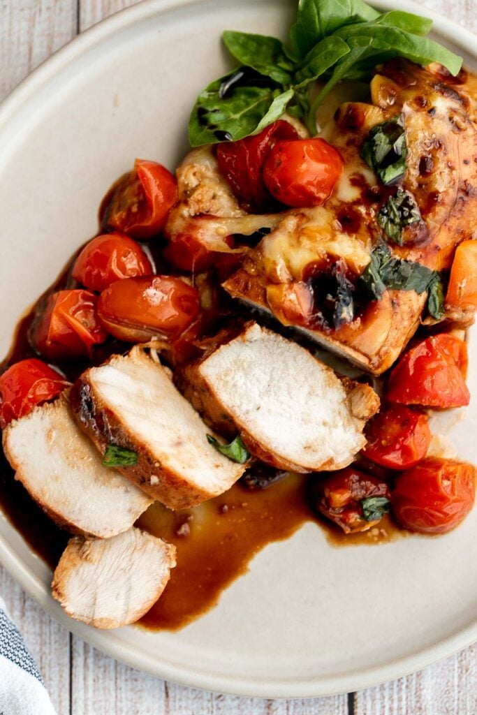 Baked caprese chicken is tender, juicy, and delicious, topped with burst tomatoes, mozzarella cheese, fresh basil, and a drizzle of balsamic glaze. | aheadofthyme.com