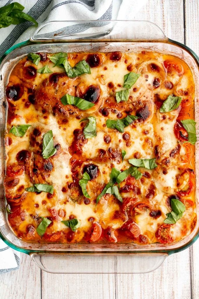 Baked caprese chicken is tender, juicy, and delicious, topped with burst tomatoes, mozzarella cheese, fresh basil, and a drizzle of balsamic glaze. | aheadofthyme.com