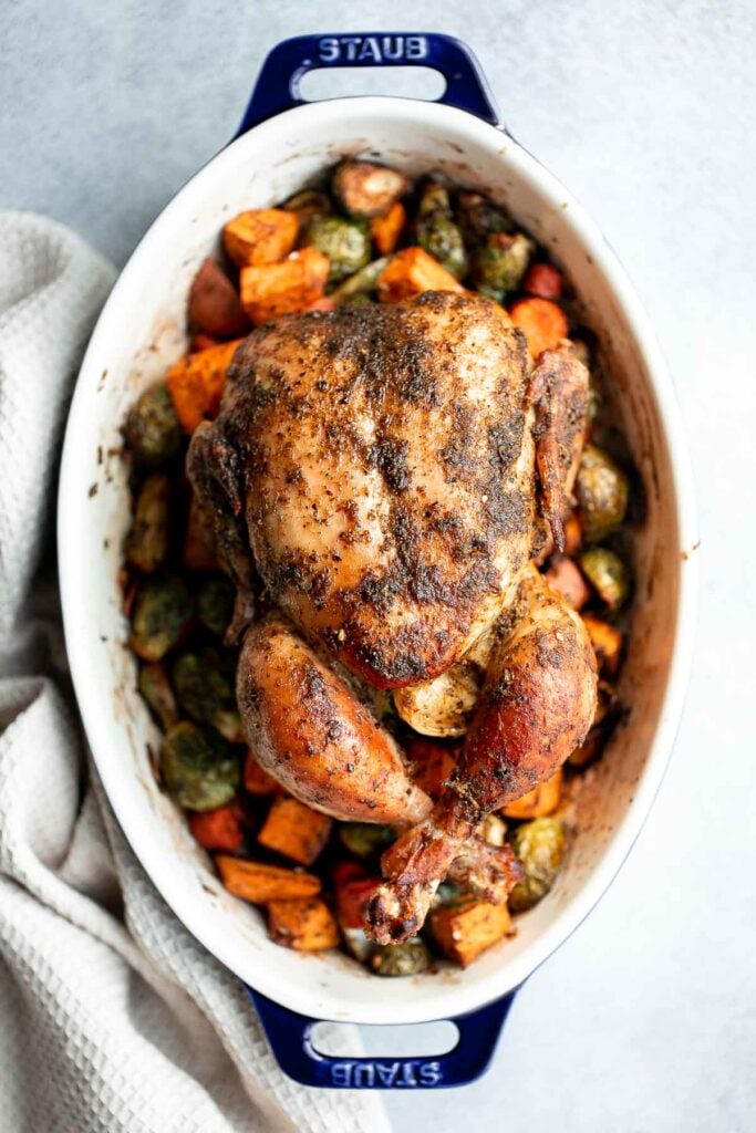 Pesto whole chicken baked over a bed of vegetables is the juiciest and most flavorful chicken you’ll ever taste. Quick and easy to prep and pop in the oven. | aheadofthyme.com