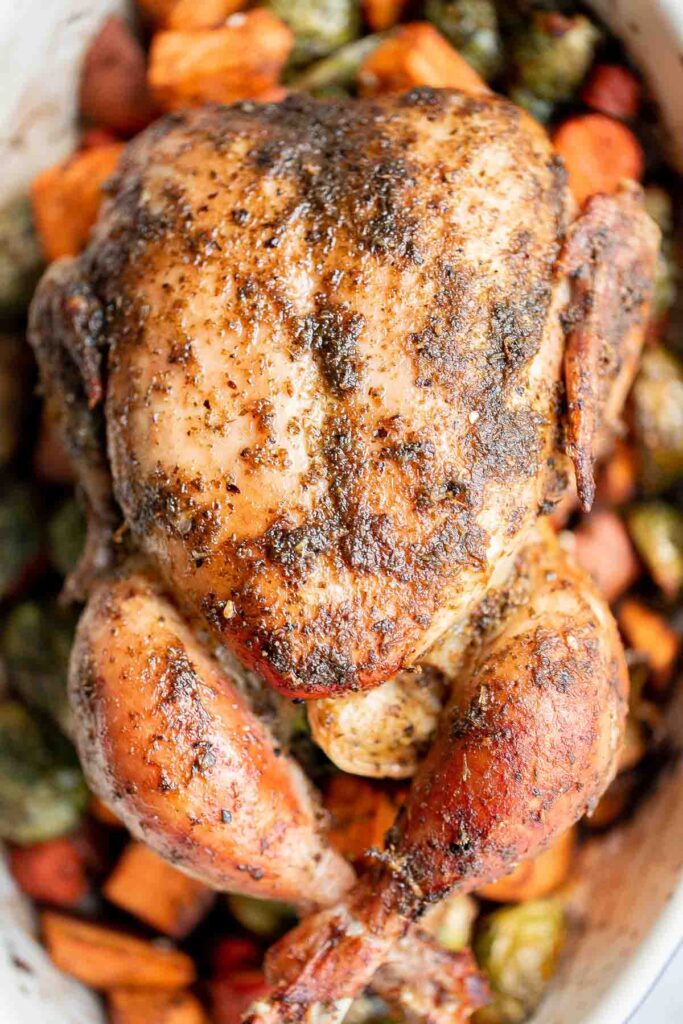 Pesto whole chicken baked over a bed of vegetables is the juiciest and most flavorful chicken you’ll ever taste. Quick and easy to prep and pop in the oven. | aheadofthyme.com