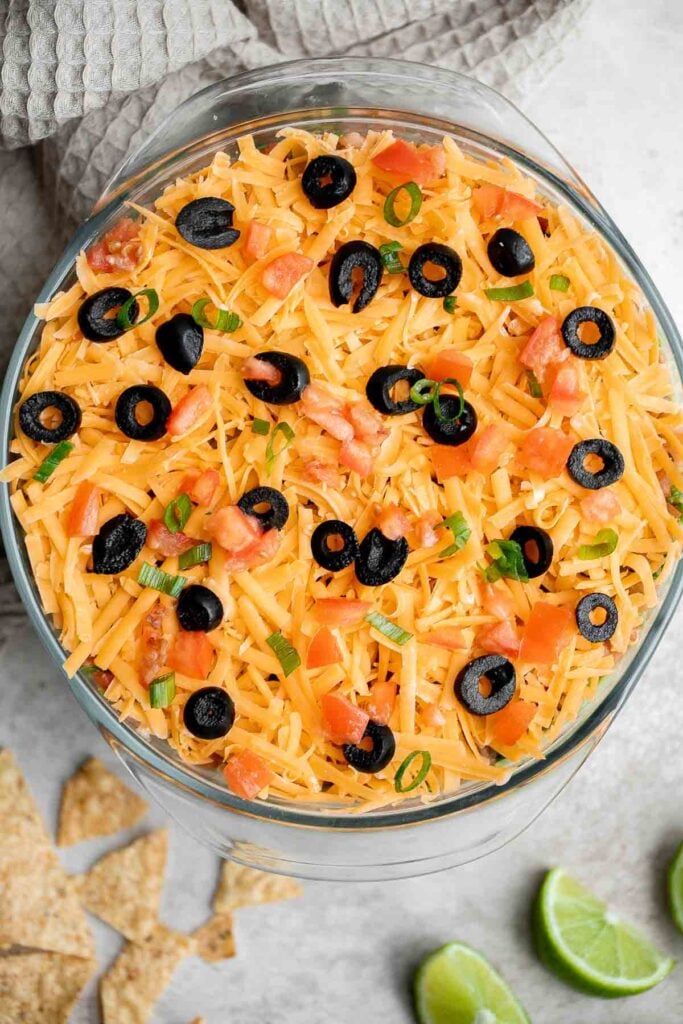 This easy and delicious 7 layer dip is the perfect dip to serve at your next party, made with layers of beans, guacamole, salsa, cheese, and more. | aheadofthyme.com