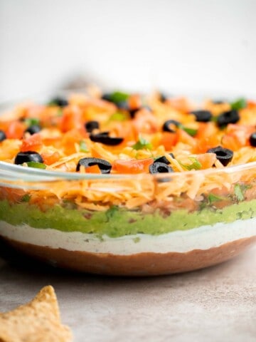 This easy and delicious 7 layer dip is the perfect dip to serve at your next party, made with layers of beans, guacamole, salsa, cheese, and more. | aheadofthyme.com