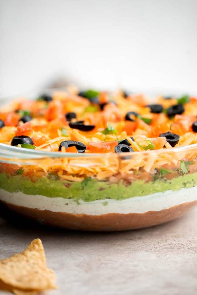 This easy and delicious 7 layer dip is the perfect dip to serve at your next party, made with layers of beans, guacamole, salsa, cheese, and more. | aheadofthyme.com