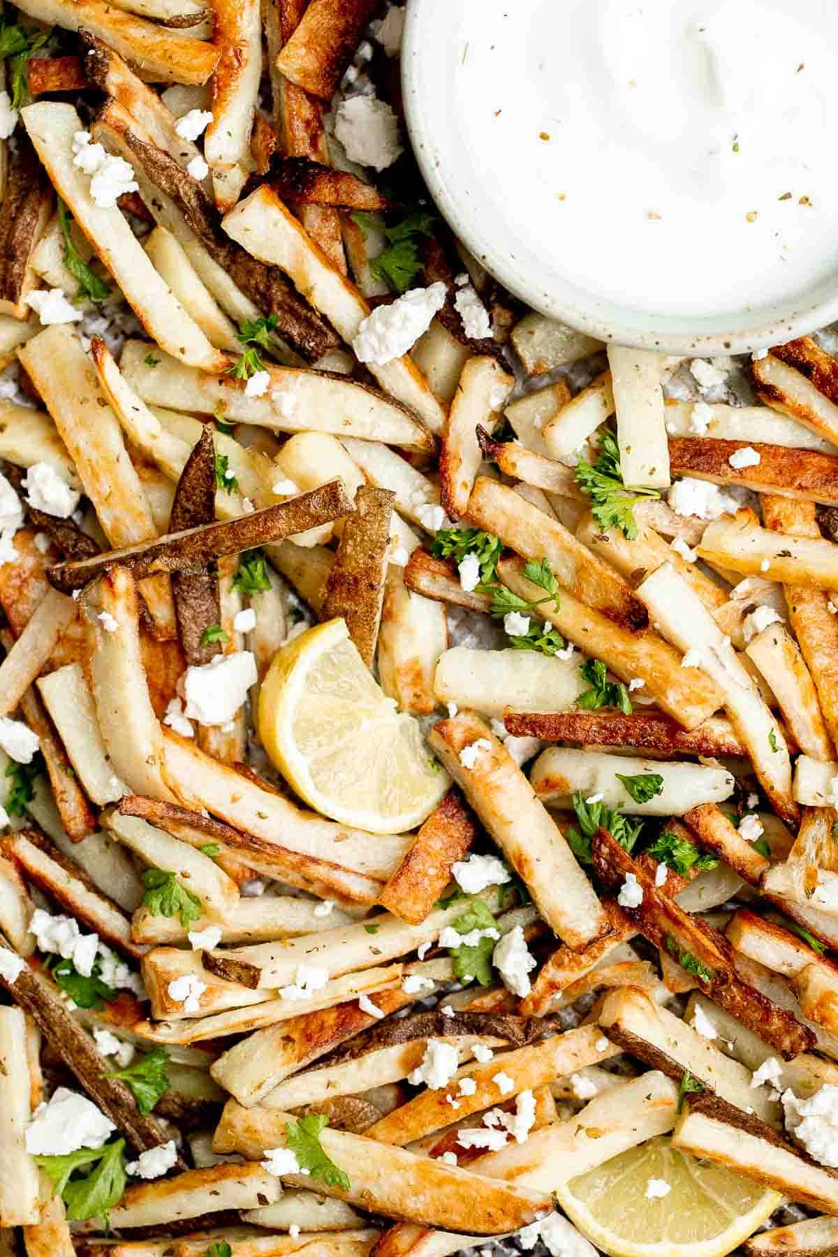 Homemade Greek fries bring a Mediterranean twist on a classic side dish, crispy fries are topped with crumbled feta cheese, fresh parsley, and lime juice. | aheadofthyme.com