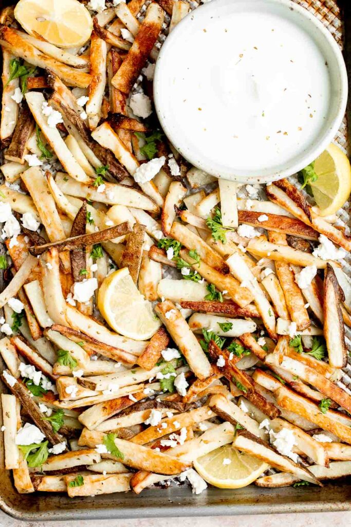 Homemade Greek fries bring a Mediterranean twist on a classic side dish, crispy fries are topped with crumbled feta cheese, fresh parsley, and lime juice. | aheadofthyme.com