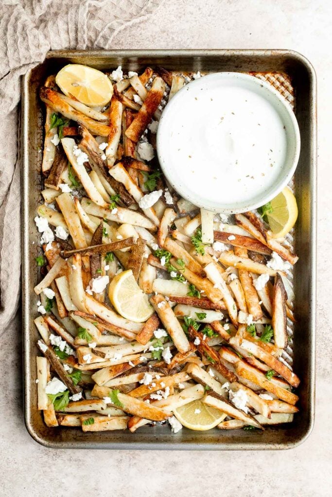 Homemade Greek fries bring a Mediterranean twist on a classic side dish, crispy fries are topped with crumbled feta cheese, fresh parsley, and lime juice. | aheadofthyme.com