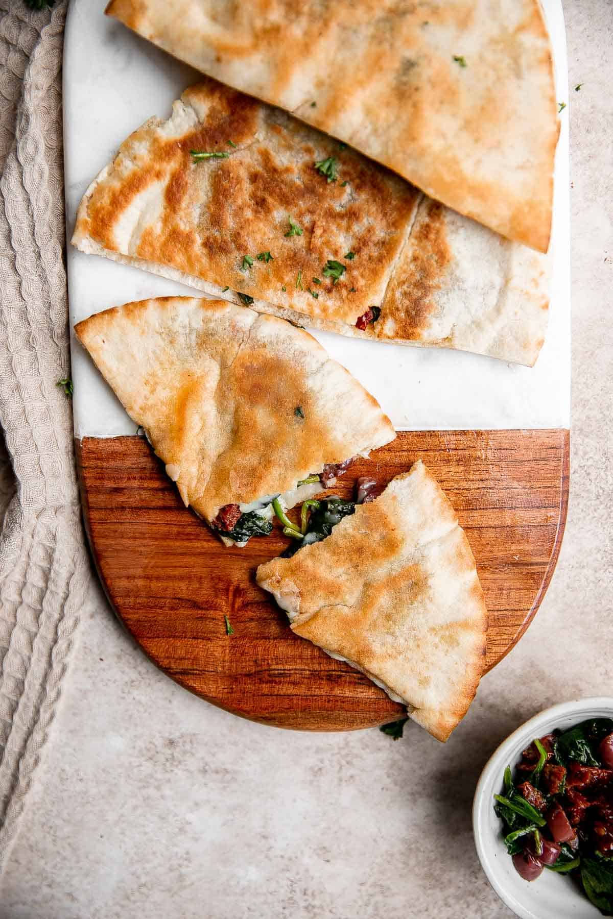 Quick easy pita grilled cheese is loaded with Mediterranean flavors of spinach, olive, and sun-dried tomato stuffed inside pita bread with cheddar cheese. | aheadofthyme.com