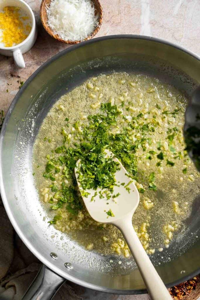 Adding fresh parsley to the lemon butter sauce.