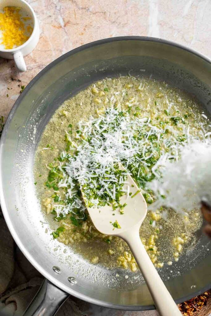 Adding freshly grated Parmesan cheese to the lemon butter sauce.