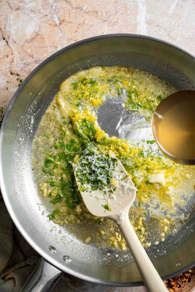 Stirring reserved pasta water into the lemon butter sauce.
