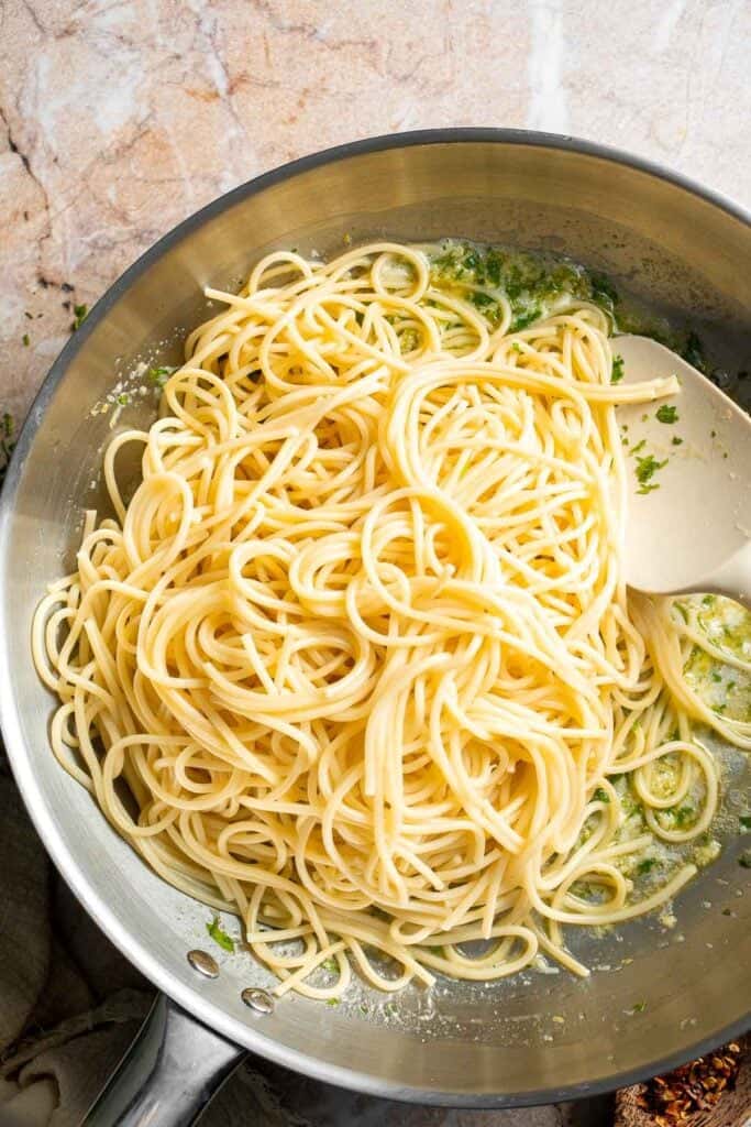 Adding cooked spaghetti to the lemon butter sauce.